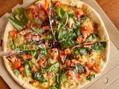 Taze pişmiş pizza bir disk bıçağıyla parçalara ayrılır. Yukarıdan görüntüle.