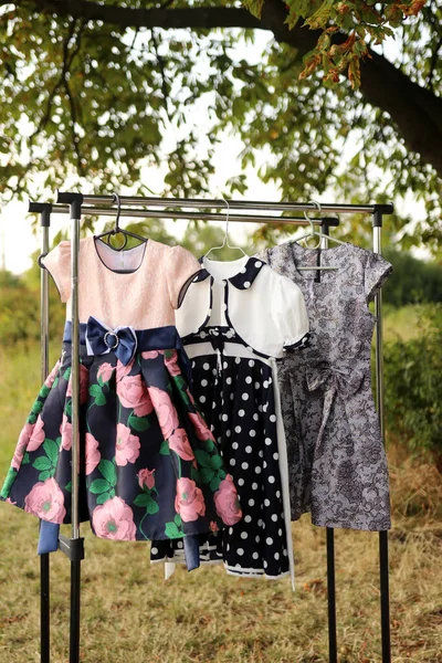 Τρία Κομψά Παιδικά Φορέματα Κρέμονται Στις Κρεμάστρες — Φωτογραφία Αρχείου