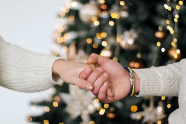 Adam, Noel ağacının arka planında kızın elini tutuyor. Samimiyet, aşk, aile.