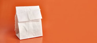 Turuncu arka planda iplikle dikilmiş kağıt torba. Yiyecek ürünlerinin ambalajı.