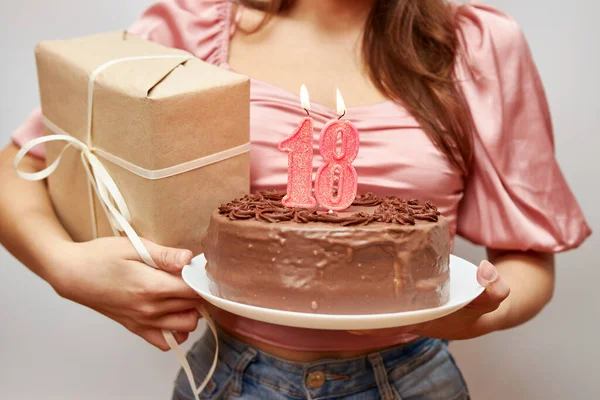 Kız elinde 18 numara şeklinde bir mum ve bir hediyeyle şenlikli bir pasta tutuyor. Doğum günü kutlaması konsepti.