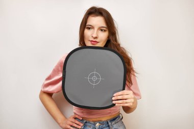 A beautiful girl holds a card for registering the correct white balance.