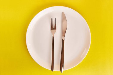 Çatallı beyaz tabak ve gri arka planda bıçak..