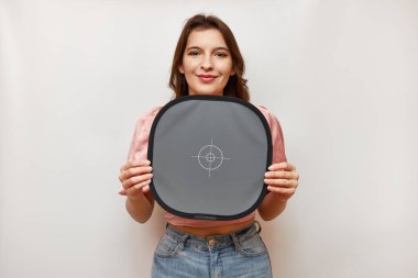 A beautiful girl holds a card for registering the correct white balance.