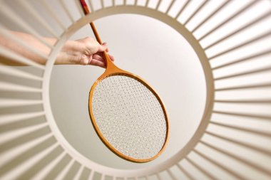 A badminton racket is thrown into the trash for disposal and recycling. View from below. The concept of disposal and processing of waste.