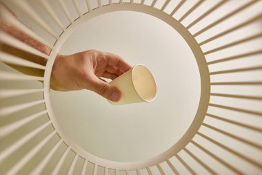 The paper cup is thrown into the trash for disposal and recycling. View from below. The concept of utilization and processing of waste.