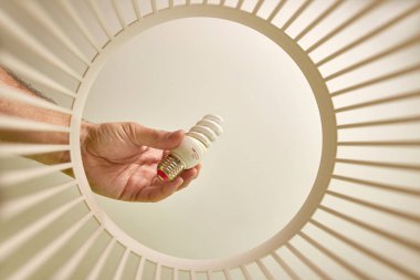 A broken energy-saving light bulb is thrown into the trash for disposal and recycling. View from below. The concept of utilization and processing of waste.