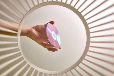 The DVD disc is thrown into the trash for disposal and recycling. View from below. The concept of disposal and processing of waste.