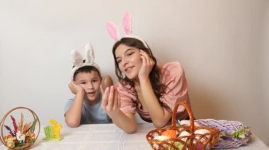 A girl and her younger brother play while tasting a chocolate egg. Celebrating Easter in the family. Easter games and fun.