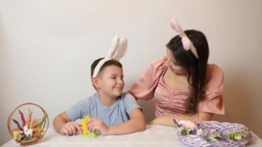 The girl covers her brother's eyes and makes an Easter surprise for him. Celebrating Easter in the family. Easter games and fun.