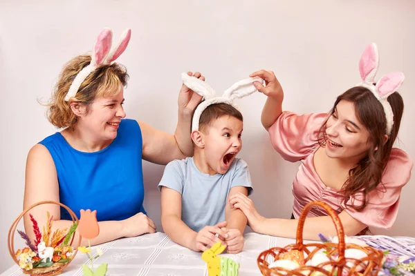 Mother, daughter and son trying on rabbit ears. Celebrating Easter in the family. Easter games and fun.