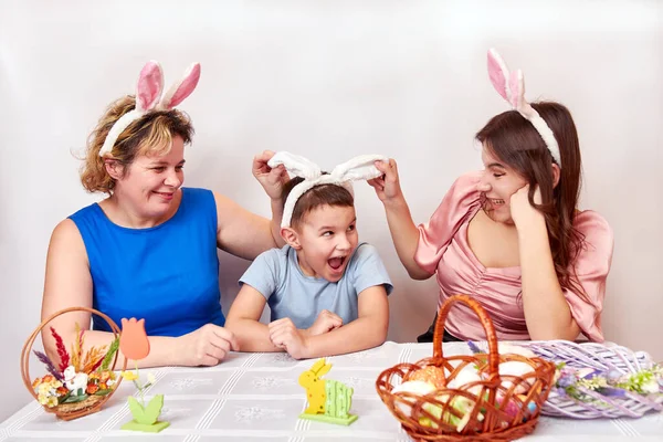 Mother, daughter and son trying on rabbit ears. Celebrating Easter in the family. Easter games and fun.
