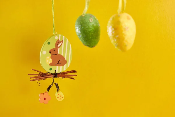 Easter beauty with a hanging rabbit and eggs on a yellow background. Easter celebration.