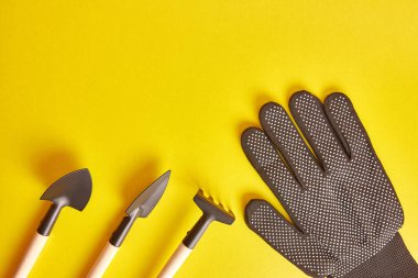 Garden tools and gloves on a yellow background. Graphic background for gardening concept.