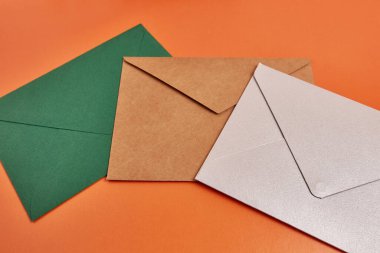Colored cardboard envelopes on an orange background.