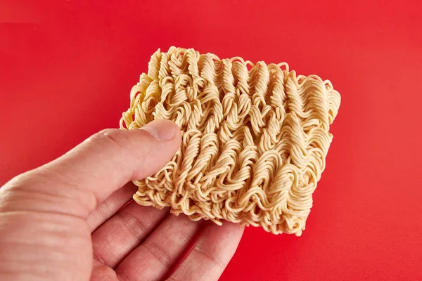 They are holding instant vermicelli on a red background. Instant food.