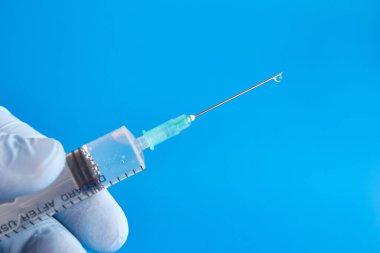 A medical syringe is prepared for the injection, so the solution drips from the needle. Administration of drugs by injection.