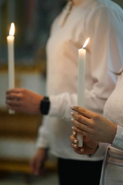 Bir kilise düğünü sırasında, gelin ve damat ellerinde mum tutarlar..