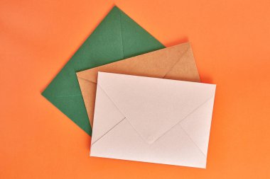 Colored cardboard envelopes on an orange background.