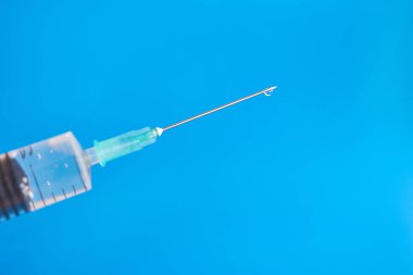 A medical syringe is prepared for the injection, so the solution drips from the needle. Administration of drugs by injection.