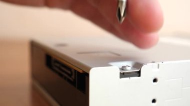 During the repair of an electronic gadget, a screw is unscrewed with a screwdriver.