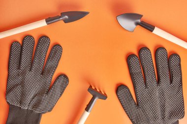 Garden tools and gloves on an orange background. Graphic background for gardening concept.