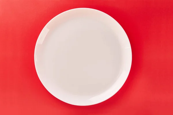 stock image White plate on a red background. Graphic background for designers.