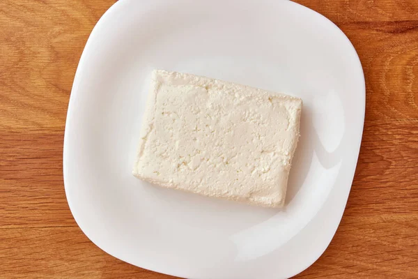 Кусок Кислого Молочного Сыра Белой Тарелке — стоковое фото