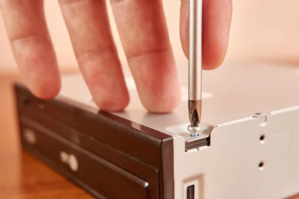 During the repair of an electronic gadget, a screw is unscrewed with a screwdriver.