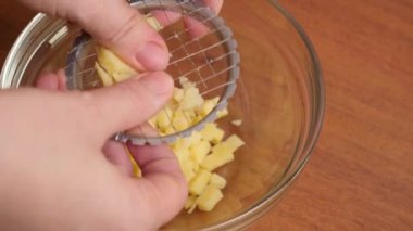 Elle dilimlemenin yardımıyla, patatesler salata hazırlığı için doğranır..