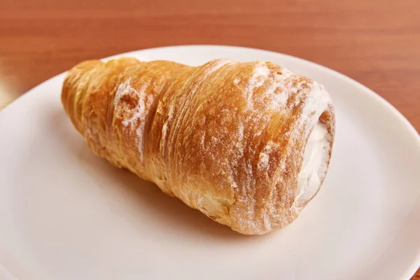 stock image Puff pastry tube with cream on a white plate.