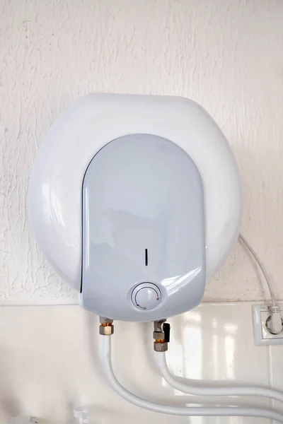 Electric water heater on the wall in the bathroom.