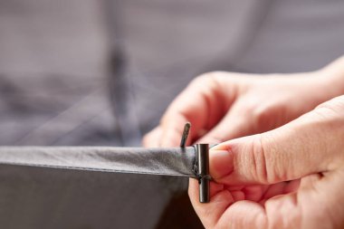 Bir zanaatkar iğneyi bir el aletiyle değiştirerek bir şemsiyeyi onarır. Ev eşyalarının küçük tamiri.