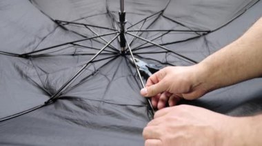 Bir zanaatkar iğneyi bir el aletiyle değiştirerek bir şemsiyeyi onarır. Ev eşyalarının küçük tamiri.