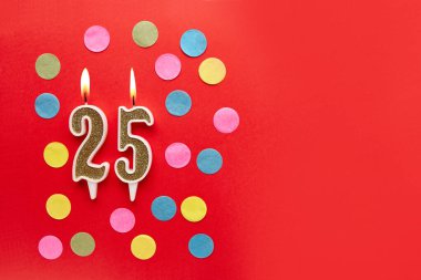 Kırmızı arka planda, renkli konfetiyle 25 numara. Mutlu doğum günü mumları. Doğum günü, yıldönümü, önemli randevu, tatil kavramı. Uzayı kopyala Pankart