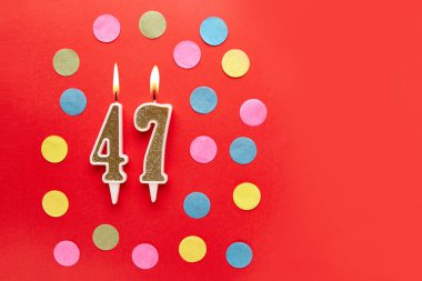 Kırmızı arka planda 47 numara ve renkli konfeti. Mutlu doğum günü mumları. Doğum günü, yıldönümü, önemli randevu, tatil kavramı. Uzayı kopyala Pankart