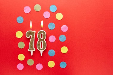 Renkli konfetiyle kırmızı arka planda 78 numara. Mutlu doğum günü mumları. Doğum günü, yıldönümü, önemli randevu, tatil kavramı. Uzayı kopyala Pankart