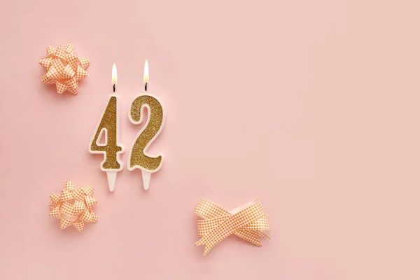 Number 42 on a pastel pink background with festive decorations. Happy birthday candles. The concept of celebrating a birthday, anniversary, important date, holiday. Copy space. banner