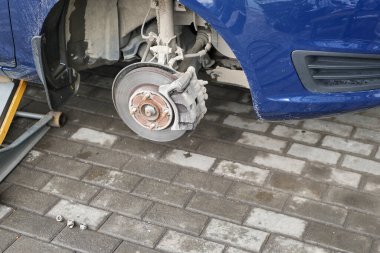 Tekerleği çıkarılmış yükseltilmiş araba. Lastik montaj istasyonu. Yaz ve kış lastiklerinin değiştirilmesi.