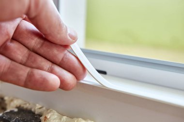Plastik kapı çerçevesine bir mühür yapıştırılmış. Metal-plastik yapıların bakımı. Enerji tasarrufu inşaat teknolojileri.