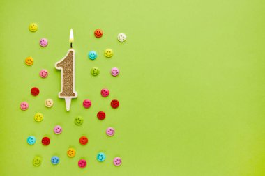 Renkli yüz ifadeleriyle pastel yeşil arka planda bir numara. Mutlu doğum günü mumları. Doğum günü, yıldönümü, önemli randevu, tatil kavramı. Uzayı kopyala Pankart