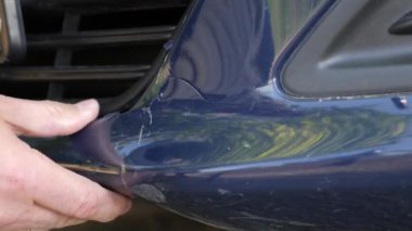 Kazadan sonra arabanın plastik tamponundaki çatlağı kontrol ediyorlar. Araba kazaları ve tamir işleri..