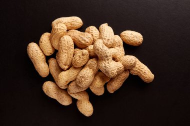 Siyah arka planda kabuksuz fıstık yığını. Lezzetli ve sağlıklı yemekler hazırlamak için bir malzeme..