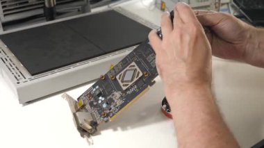 Bir hizmet merkezi çalışanı GPU çipini lehimlemek için video kartına bacaklar ekler.