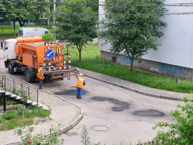 İşçiler, özel bir araç ve teçhizat yardımıyla yol yüzeyini onarıyor.