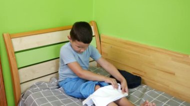 Çocuk giysilerini dikkatlice katlıyor. Ev ödevi. Yıkama, ütüleme ve katlama.