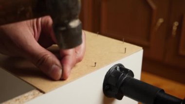 Dolabın arka duvarı çivi ve çekiçle çivilenmiş. Dolap mobilyalarının montajı.