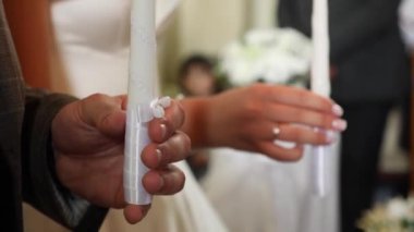 The bride and groom hold candles in the church during the wedding ceremony.