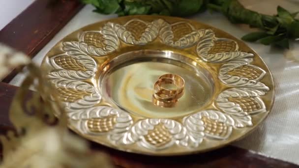Arany Jegygyűrűk Egy Tányéron Egy Templomi Esküvő Alatt — Stock videók