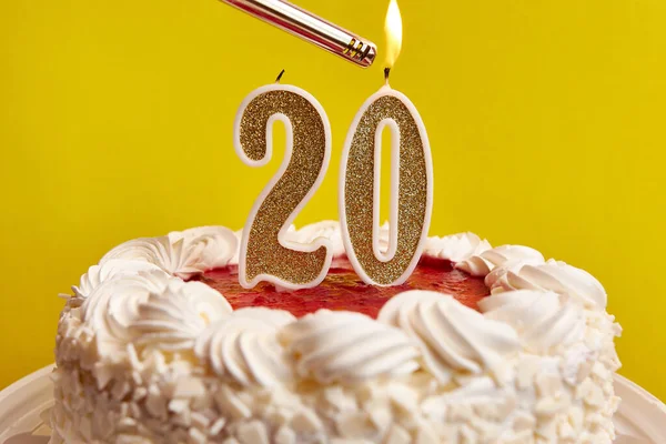 A candle in the form of the number 20, stuck in a festive cake, is lit. Celebrating a birthday or a landmark event. The climax of the celebration.